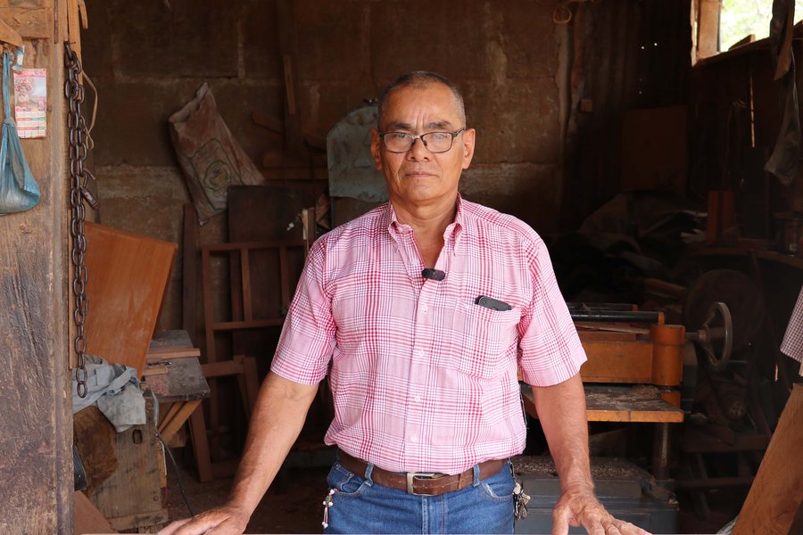 Eugenio Antonio Oporta en la entrada de su taller de carpintería, con una mesa de madera terminada