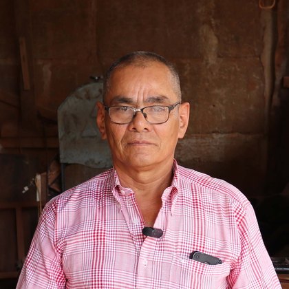 Eugenio Antonio Oporta en su taller de carpintería, apoyado en una mesa de madera recién terminada